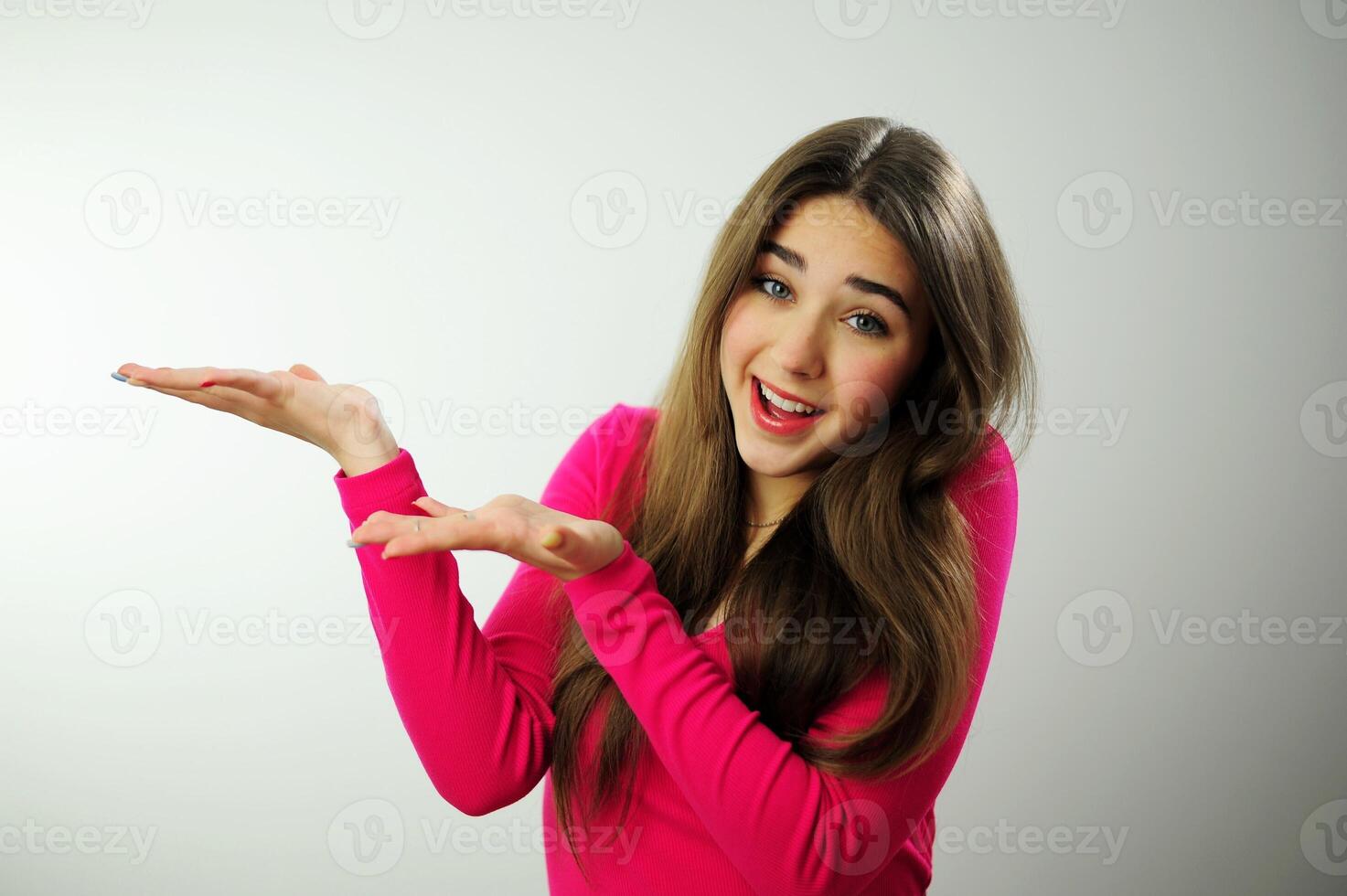 Hey look. Smiling pretty female model pointing fingers left at empty space and inviting to check it out, showing advertisement on white background woman showing hand for product advertising photo