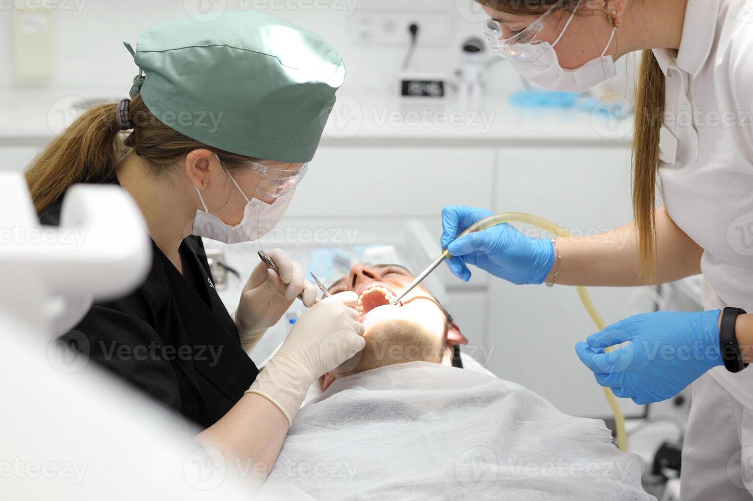 close-up shot of female dentist examining teeth of young happy client photo