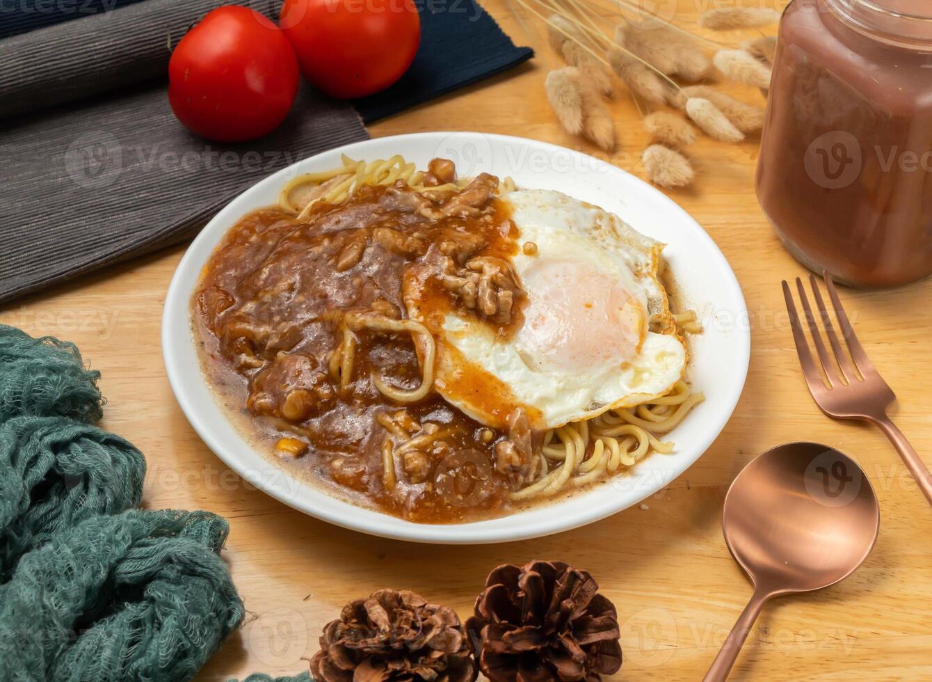 Sand tea pork fillet and egg teppanyaki noodles with cherry tomato, spoon and fork served in dish isolated on wooden table side view of taiwan food photo