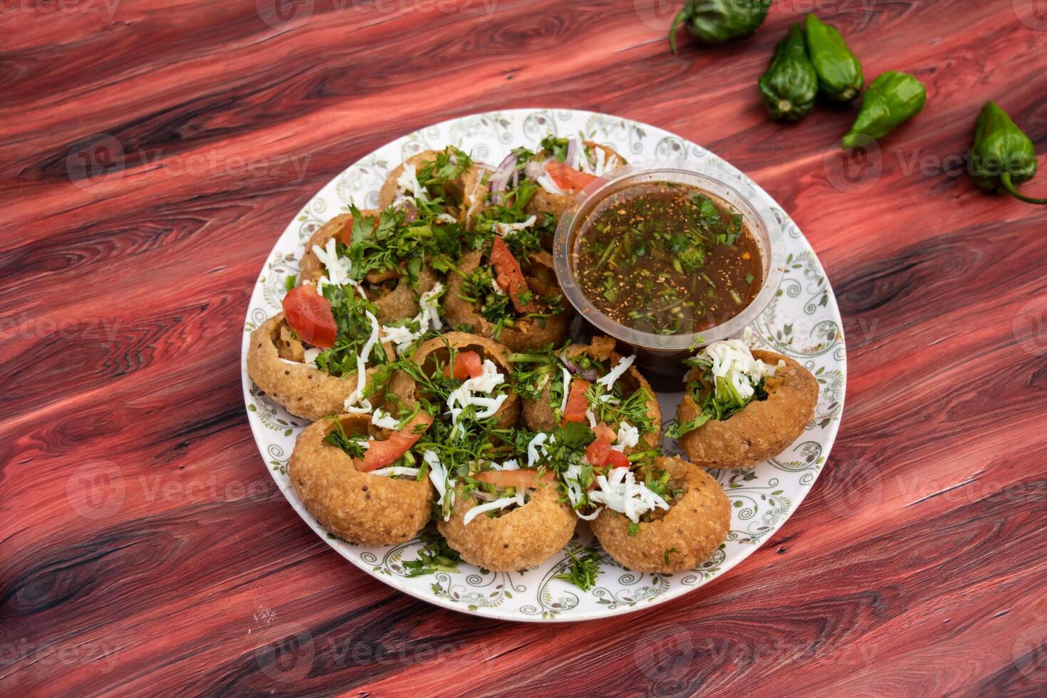 Fuchka, pan puri, or gol gappa filled with herbs with spicy water served in plate isolated on wooden table side view of bangladeshi street food photo