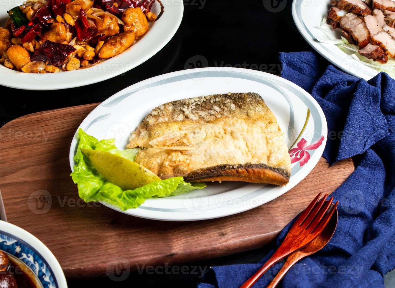 Pan fried fish maw with lemon, spoon and fork served in dish isolated on wooden board side view of taiwan food photo