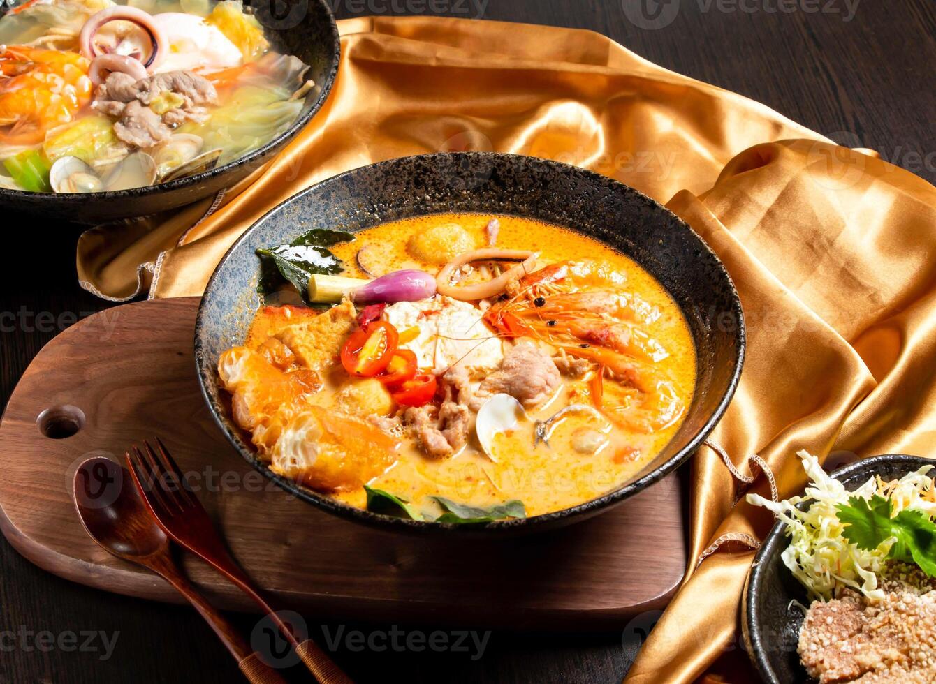 seafood and chicken pot roast with fork and spoon served in dish isolated on wooden board side view of asian food photo