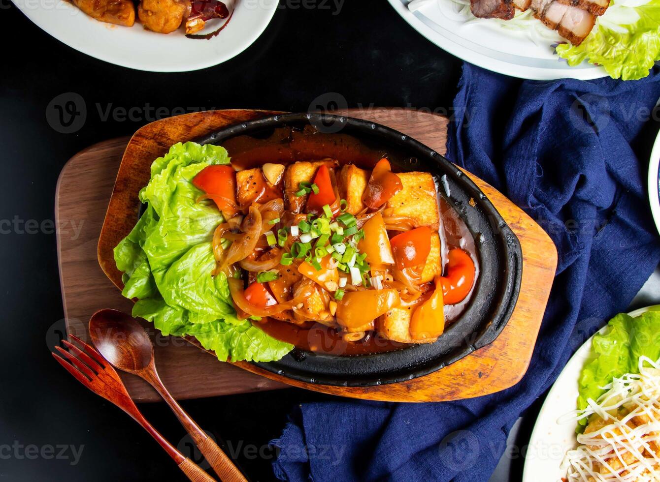 Sizzling tofu with tomato, spring onion, spoon and fork served in dish isolated on wooden board top view of taiwan food photo