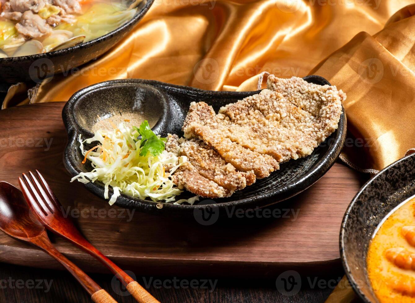 Fried pork ribs with salad, fork and spoon served in dish isolated on wooden board side view of asian food photo
