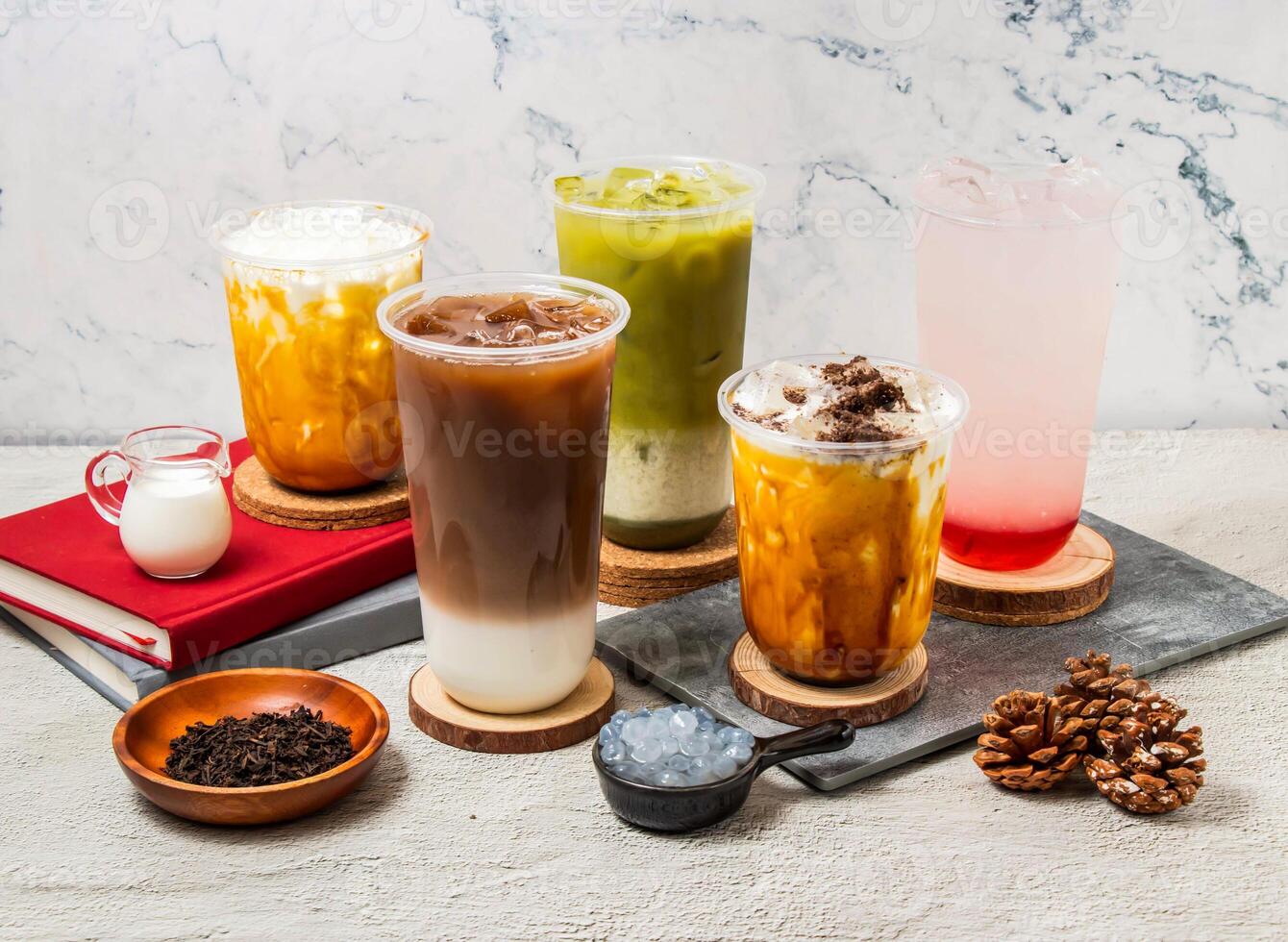 Assorted Taiwan iced tea Oolong milk Latte, Green tea latte, Strawberry Lemon tea, ice Oreo milk tea, served in disposable glass isolated on board side view of taiwanese iced drink photo