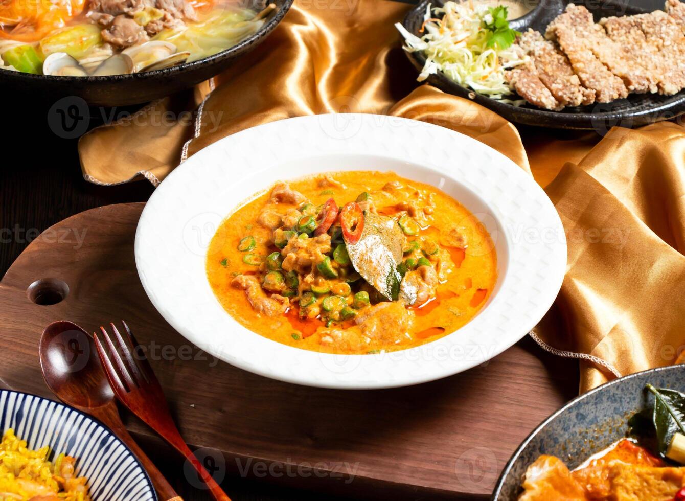 Red Curry Coconut Chicken with fork and spoon served in dish isolated on wooden board side view of asian food photo