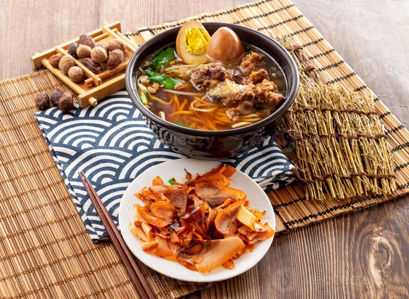 Spare ribs noodle set with pig scalp, preserved egg, chopsticks served in dish isolated on napkin side view on table taiwan food photo