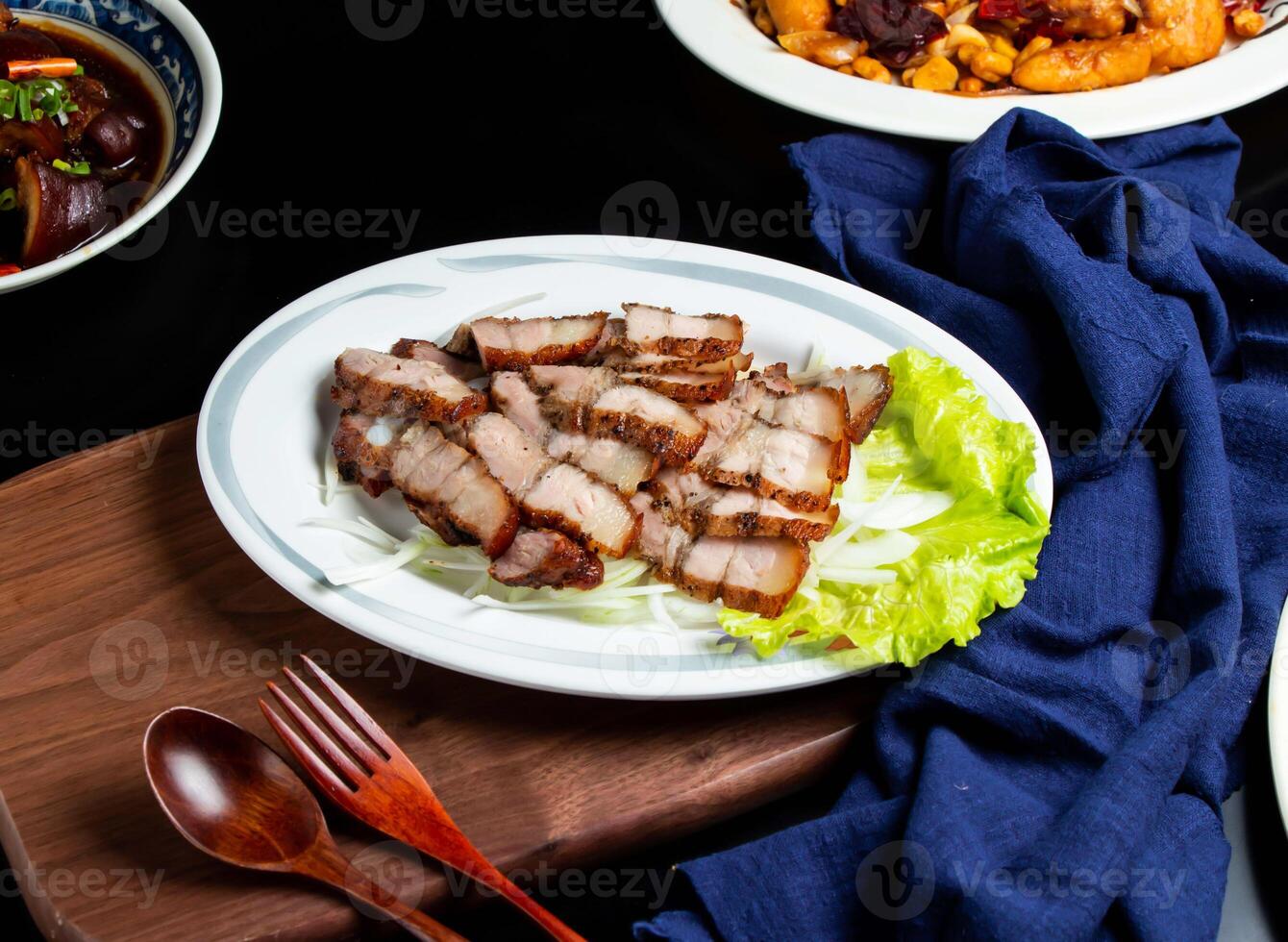 Grilled Salted Pork with spoon and fork served in dish isolated on wooden board side view of taiwan food photo