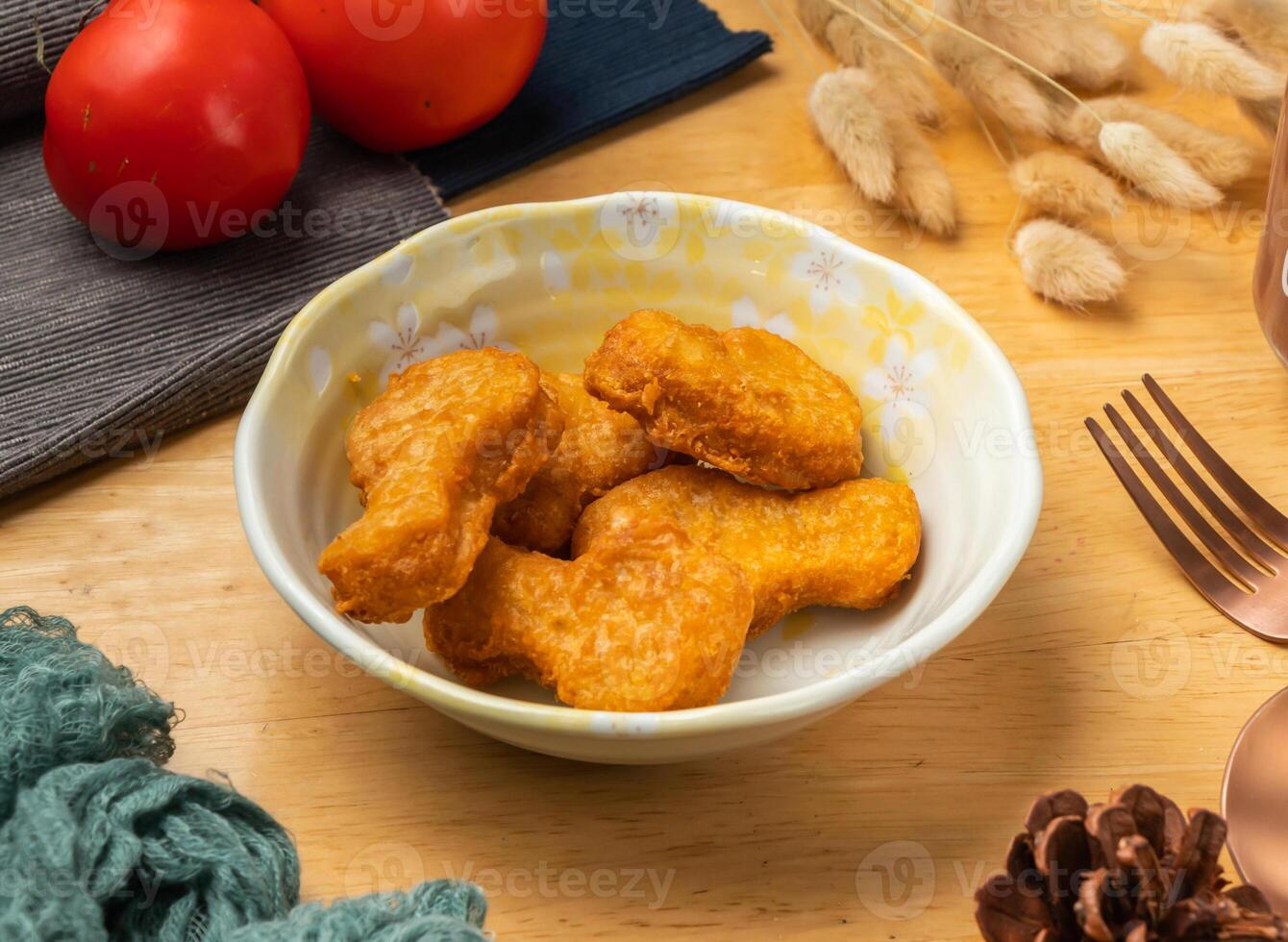 chicken nuggets with cherry tomato, spoon and fork served in dish isolated on wooden table side view of taiwan food photo