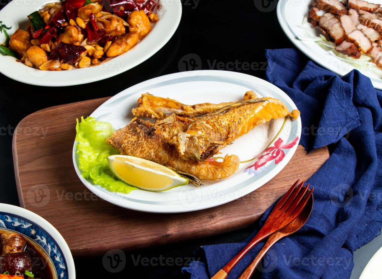 Fried Fish Jaw Roast with lemon, spoon and fork served in dish isolated on wooden board side view of taiwan food photo