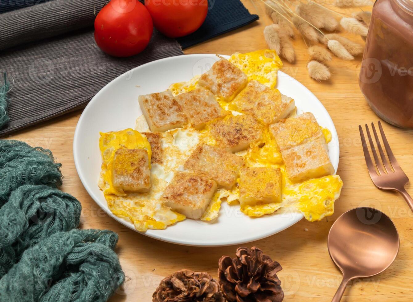 Chinese Carrot cake with egg with cherry tomato, spoon and fork served in dish isolated on wooden table side view of taiwan food photo