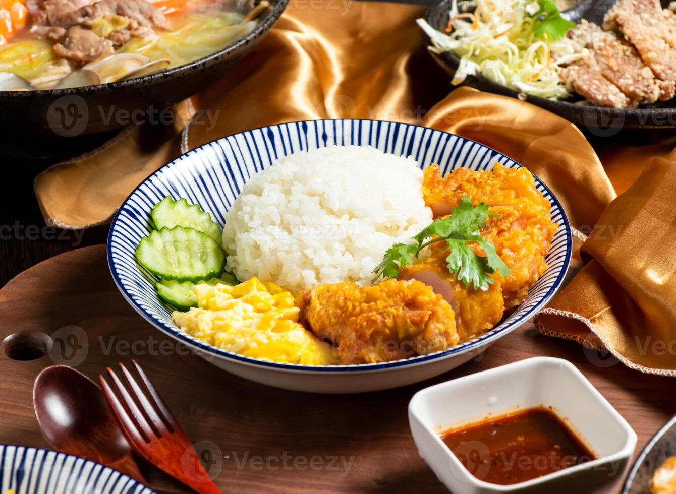 Pepper Chicken Rice with cucumber, sauce fork and spoon served in dish isolated on wooden board side view of asian food photo