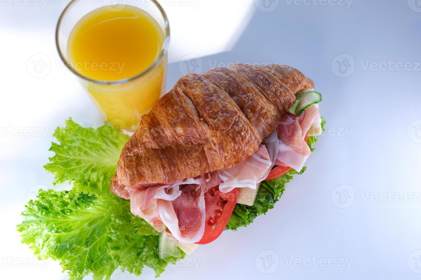 croissant sandwich with meat jamon prosciutto with tomato Lettuce food rich pieces of cheese in breakfast France on a white plate expensive restaurant hotel getting a piece of meat with a fork photo