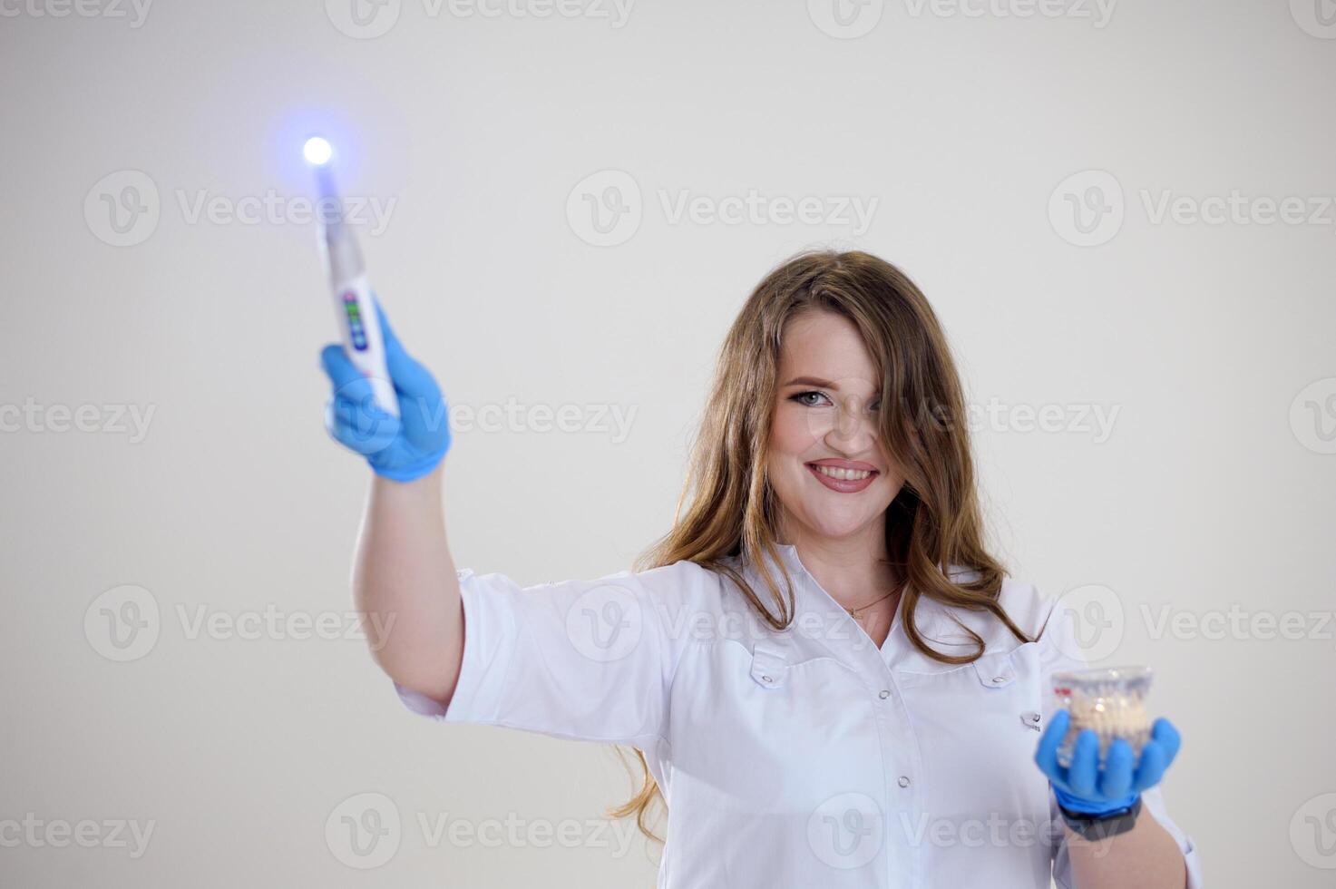 Photopolymer lamp a woman doctor like a Fairy waves a polymer lamp like a magic wand in a white suit on a white background conjures fascinates treats for children fairy tale photo