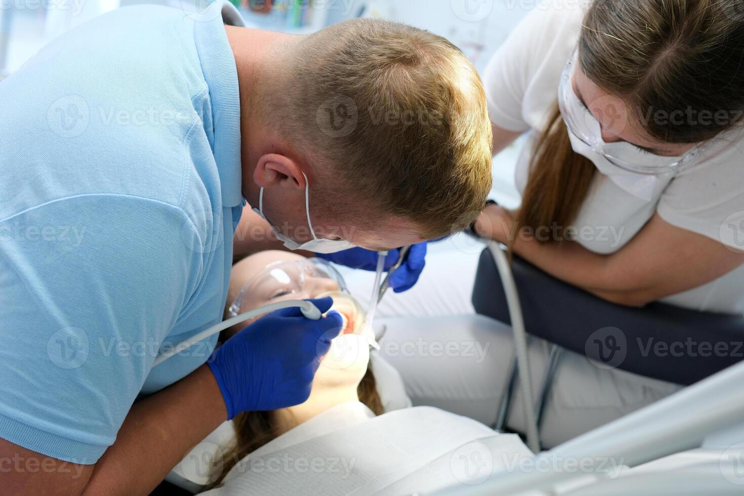 latest technology cleaning and whitening teeth nurse and doctor treating teeth of female patient teenager. latest device in a dental office in a clinic taking care of teeth snow-white smile photo