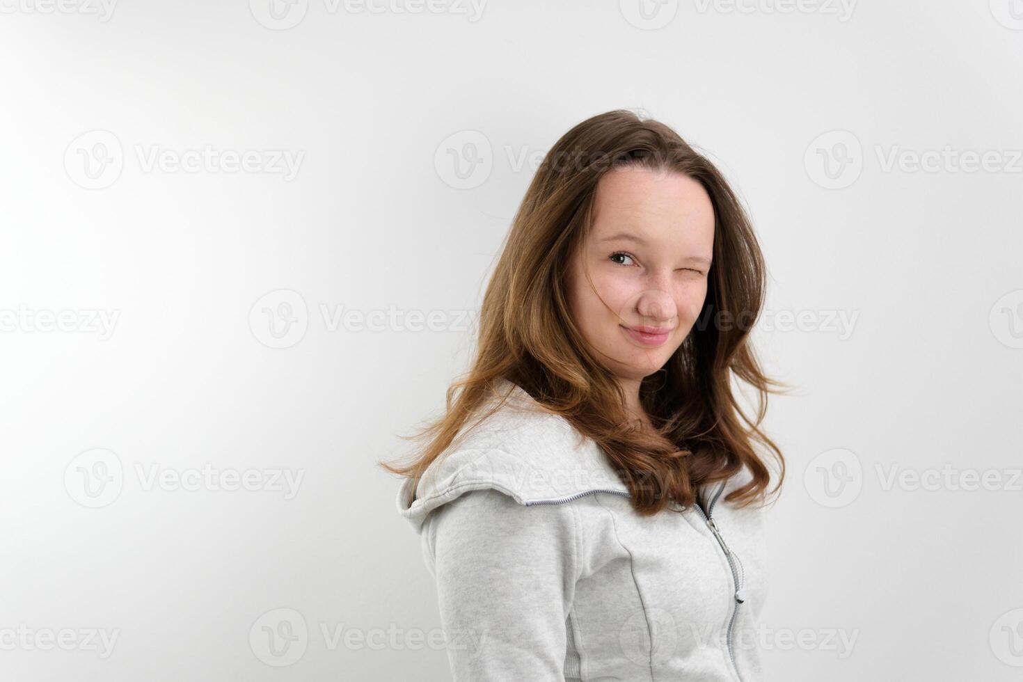 girl turns to camera smiles and blinks first with right and then with left eye light smile playfulness joke good mood on a white background in studio hair developing chic hairstyle well-groomed beauty photo