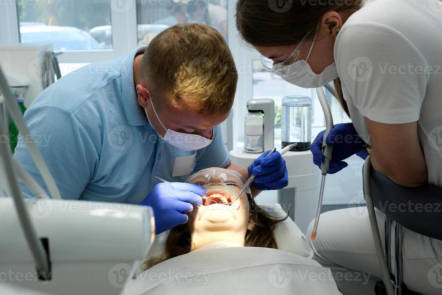 latest technology cleaning and whitening teeth nurse and doctor treating teeth of female patient teenager. latest device in a dental office in a clinic taking care of teeth snow-white smile photo