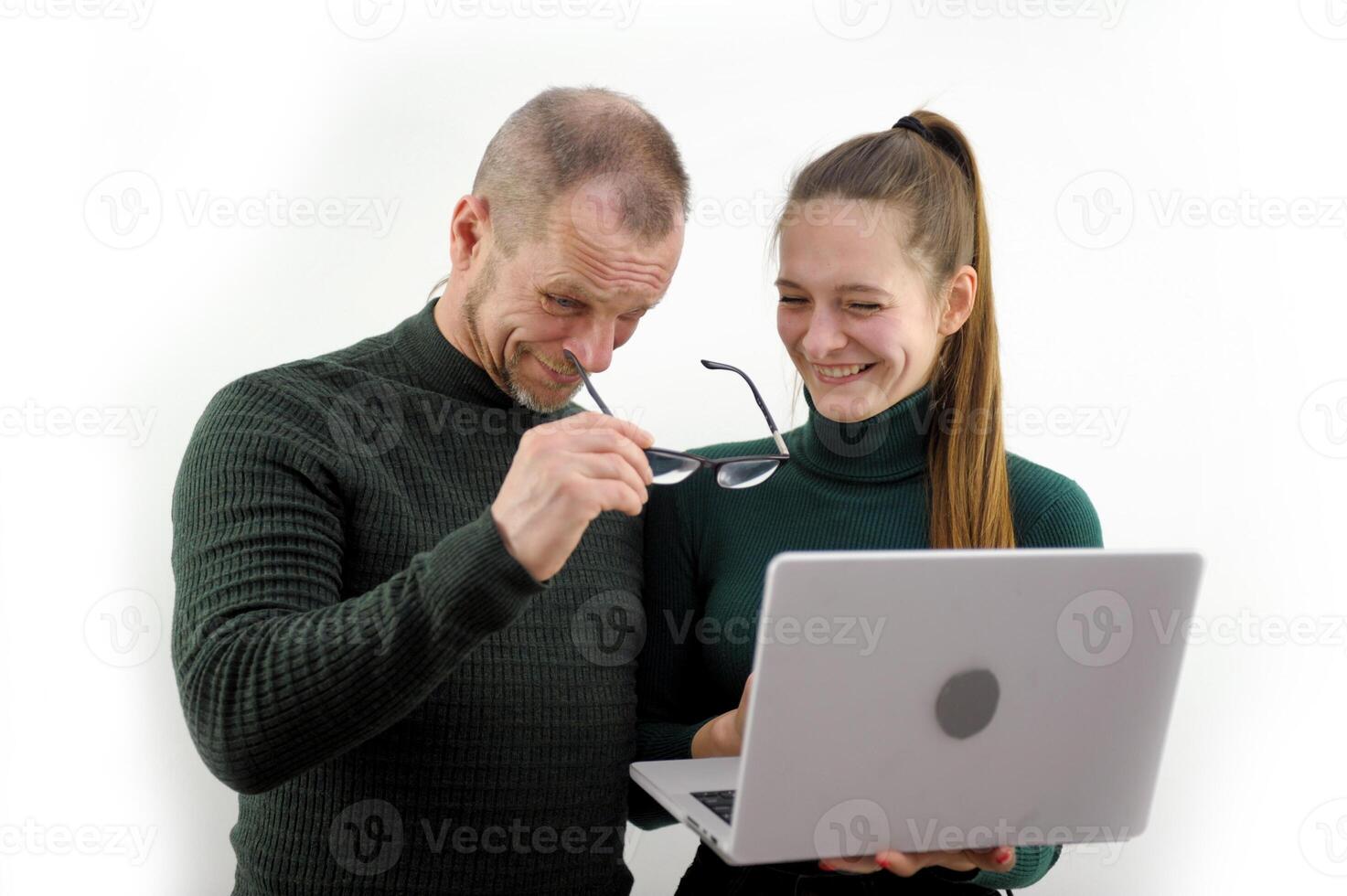 sincere laughter bewildered man through glasses looks at screen of laptop monitor Is it really so serious balding beard mustache Gray hair Green jacket white background joy winning joke embarrassment photo
