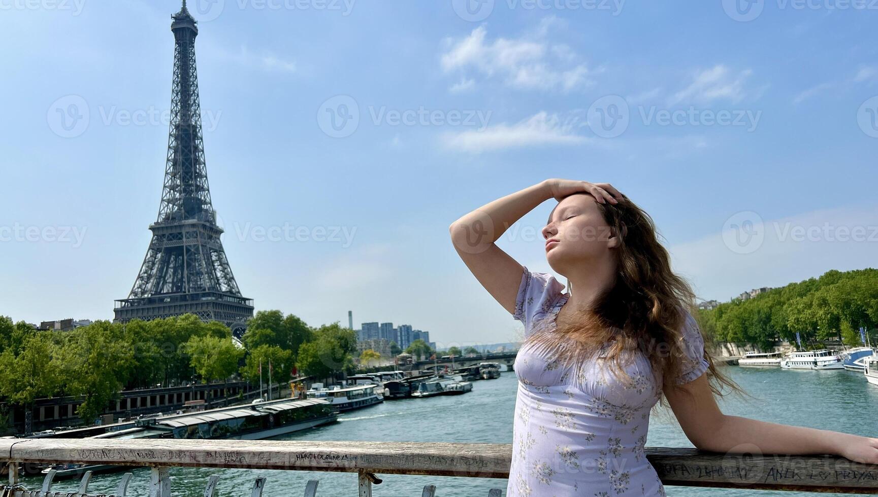 the face of a beautiful girl she is sad leaning on her arm in the distance you can see the Eiffel Tower the girl is young she is a teenager photo