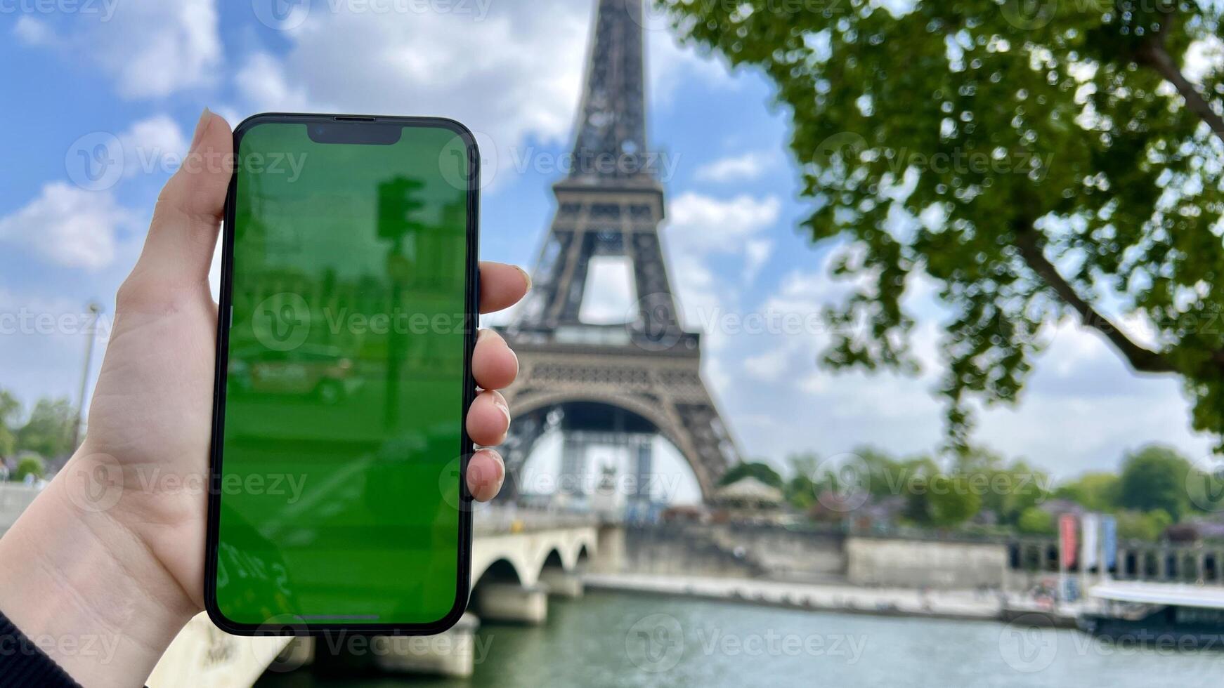 Phone with green Chromate screen on the background of the eiffel tower. in Paris using her cell phone in front of Eiffel Tower, seine bridge background, photo