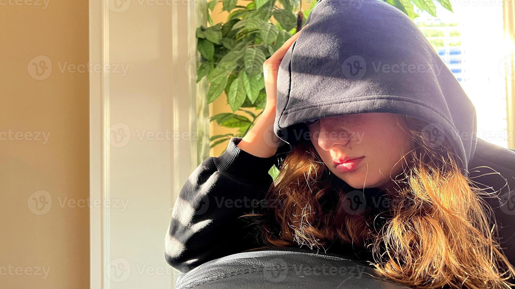 a teenage girl pulled a hood over her eyes she got angry, pressed a pillow to herself, hugged her, crossed her arms, she is angry and not satisfied with the problems of adolescence, a severe character photo