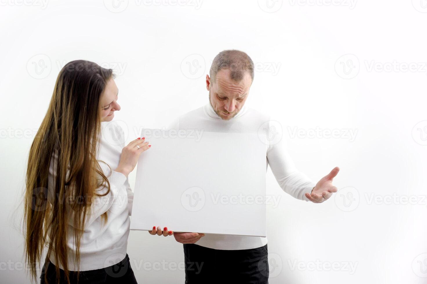 Young happy couple portrait of a confident businessman showing presentation, pointing paper placard gray background. Ideal for banners, registration forms, presentation, landings, presenting concept. photo