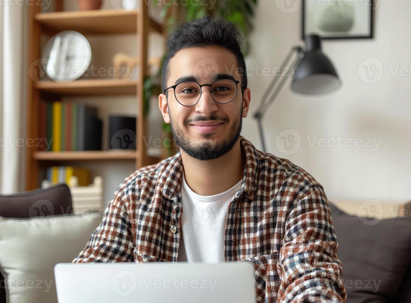 Smiling young Arab freelancer man using laptop, working remote at home. photo