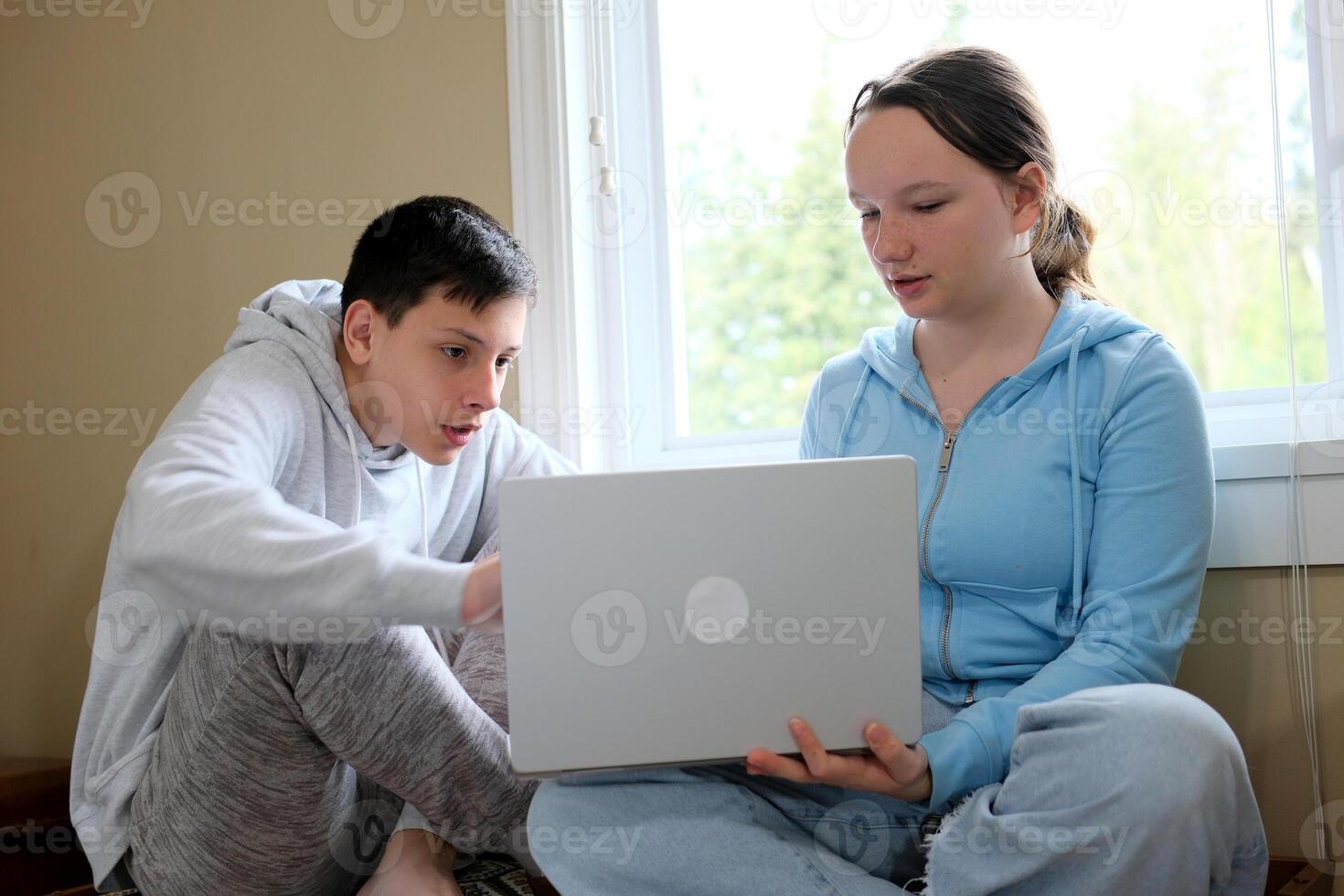 explain lesson boy showing girl on computer helping study friends older brother younger sister online learning spending time together sitting by the window with a laptop in hands teenagers photo