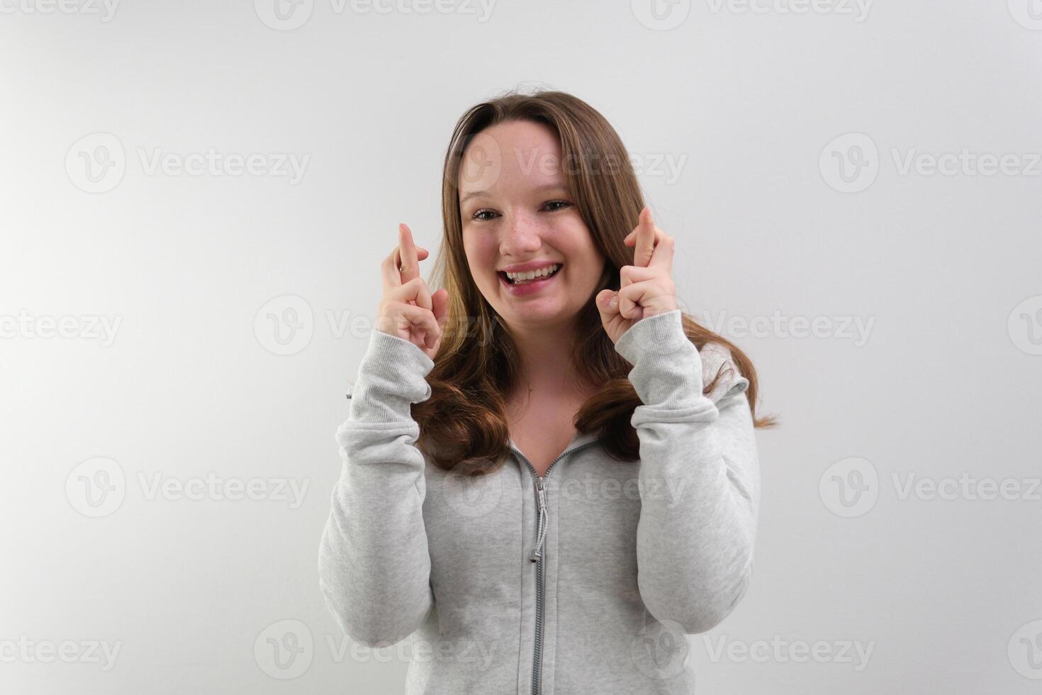 Waist-up shot of intense worried hopeful young woman waiting with anticipation for important result crossing fingers for good luck pursing lips from nervousness looking faithfully at upper left corner photo