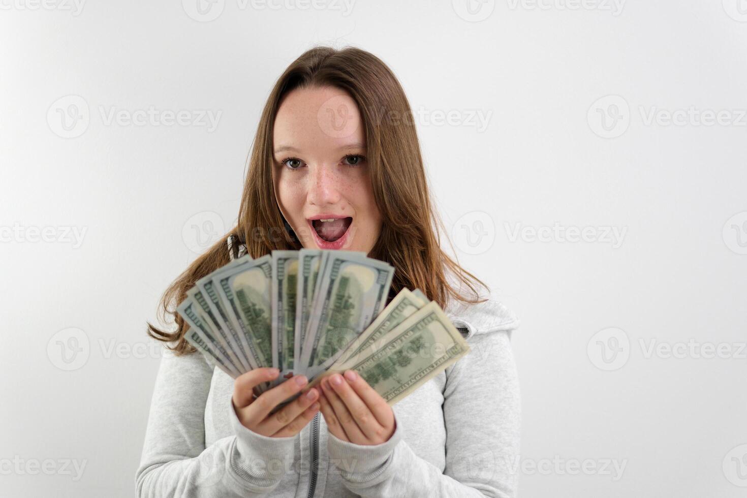 happy woman showing dollar bills money and smiling isolated on grey background photo