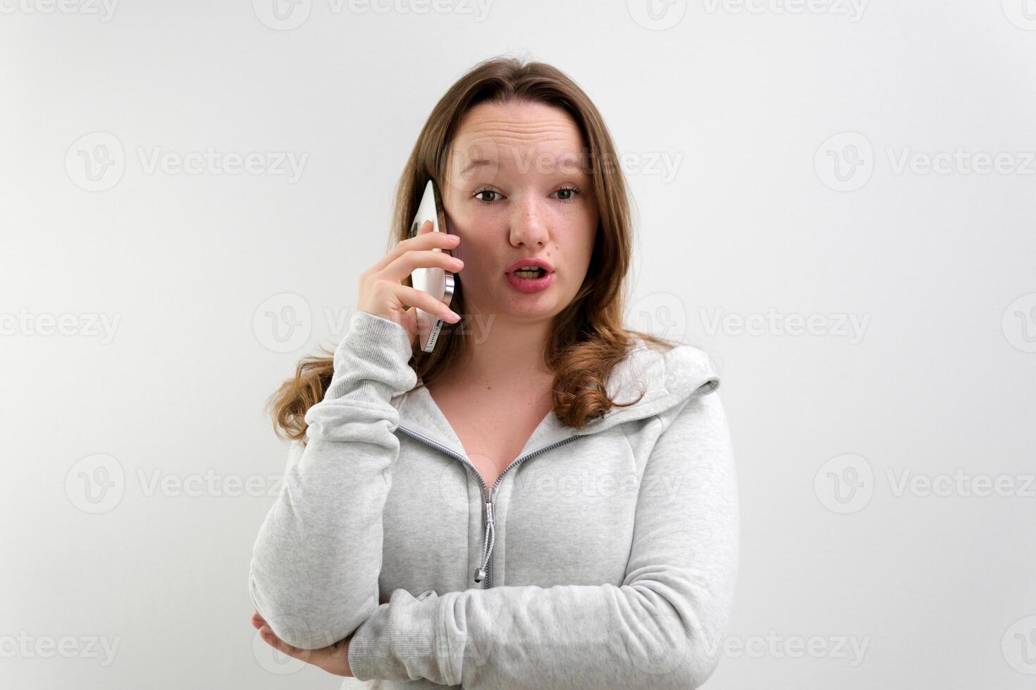 Cute high school girl with a very shocked expression talking on a cell phone photo