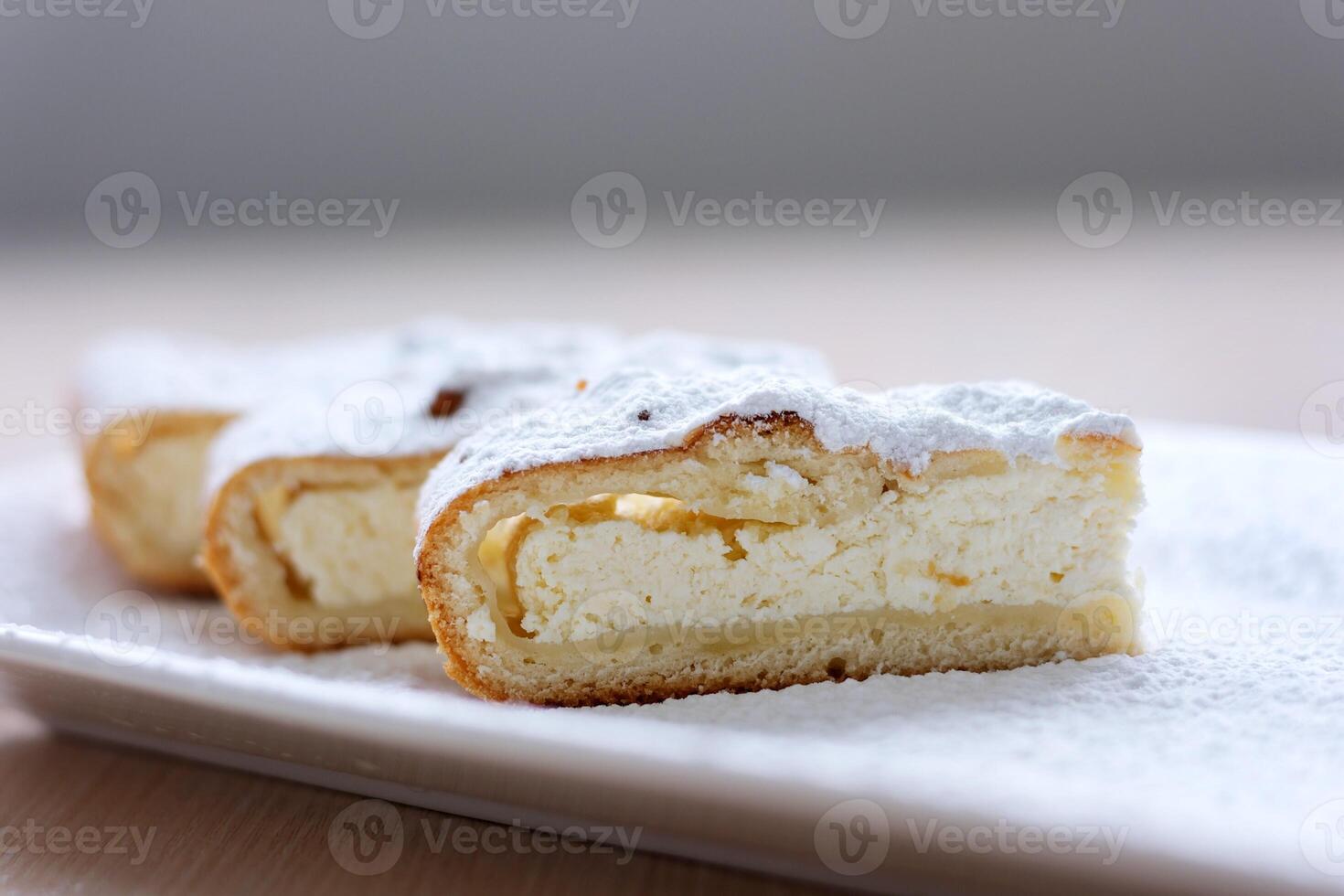 cheesecake curd strudel sliced on white plate sprinkled with powdered sugar dough is separated from curd creating drawing place for text advertising benefits of cooking show recipes restaurant serving photo