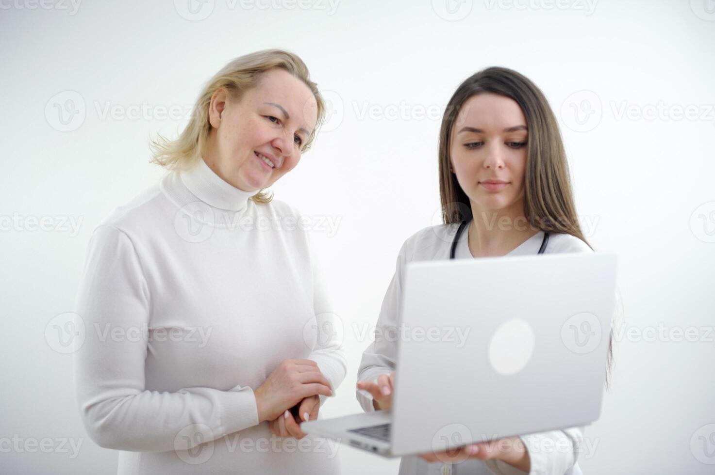 Adult doctor and young nurse with laptop on white backgrund, photo