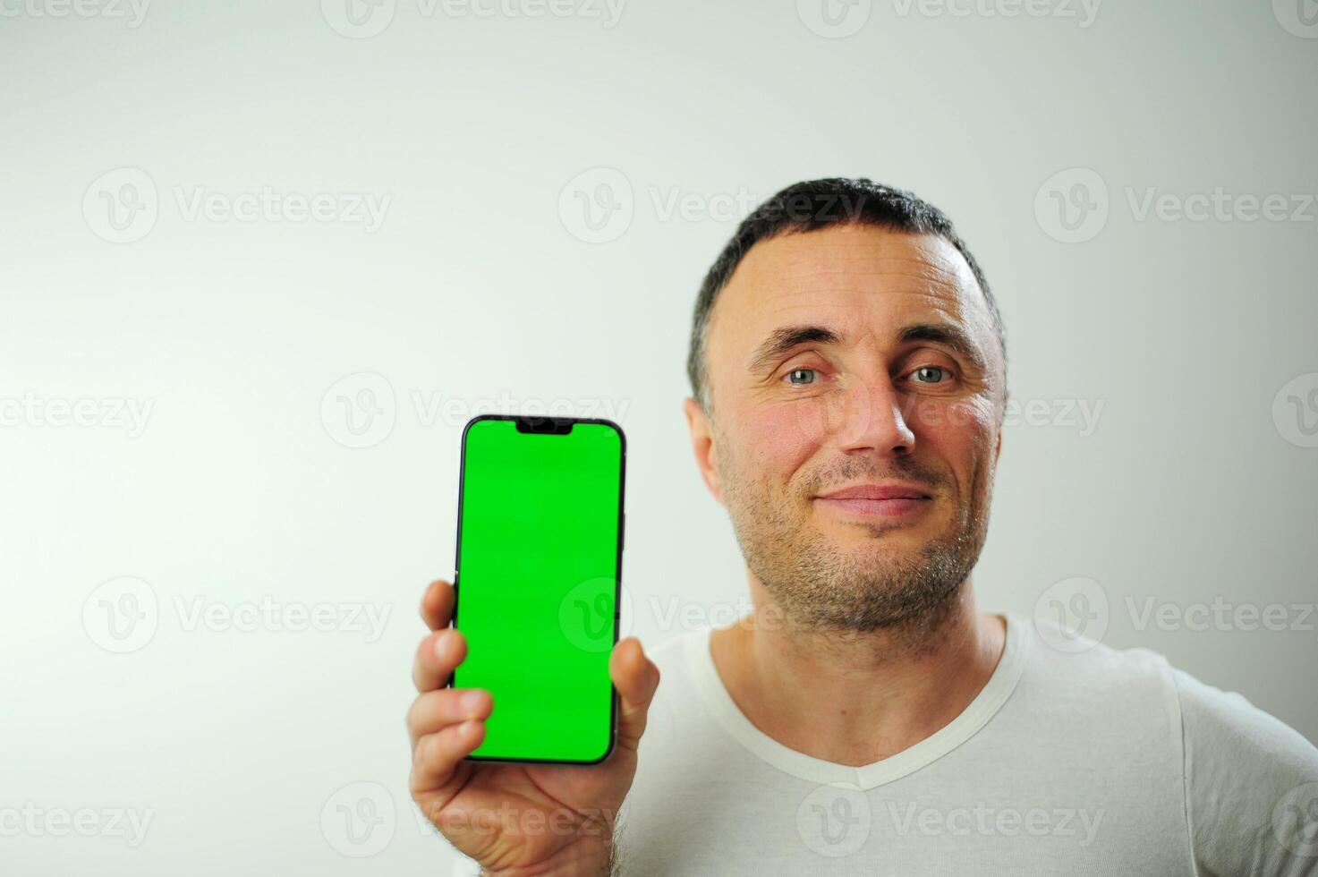 Positive millennial man showing huge brand new smartphone with empty screen and thumb up over white studio background, mockup, panorama with copy space, newest mobile app concept photo