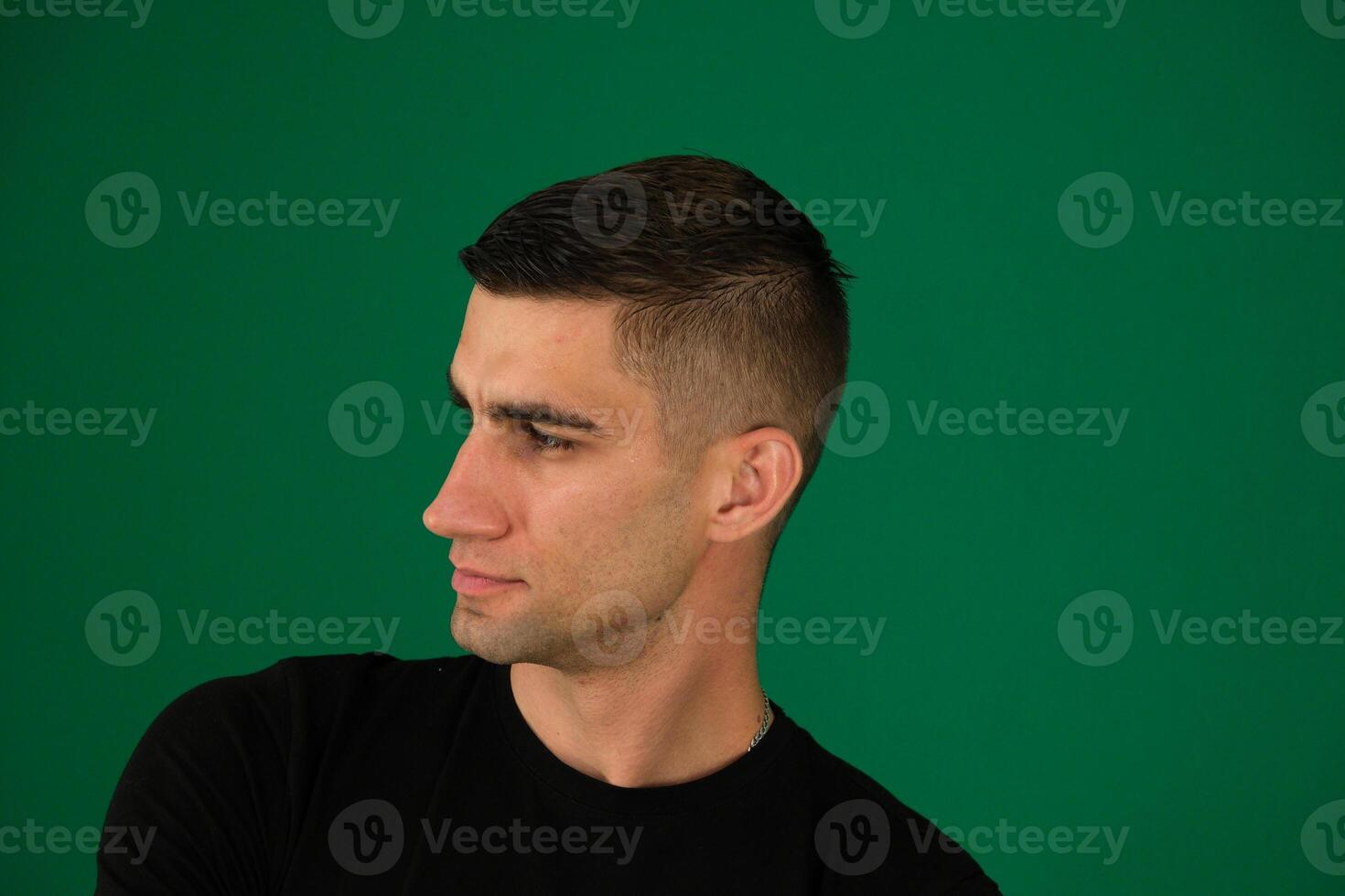 Close up profile view of young handsome man isolated against emotions of a handsome man guy on a green background chromakey close-up dark hair young man photo