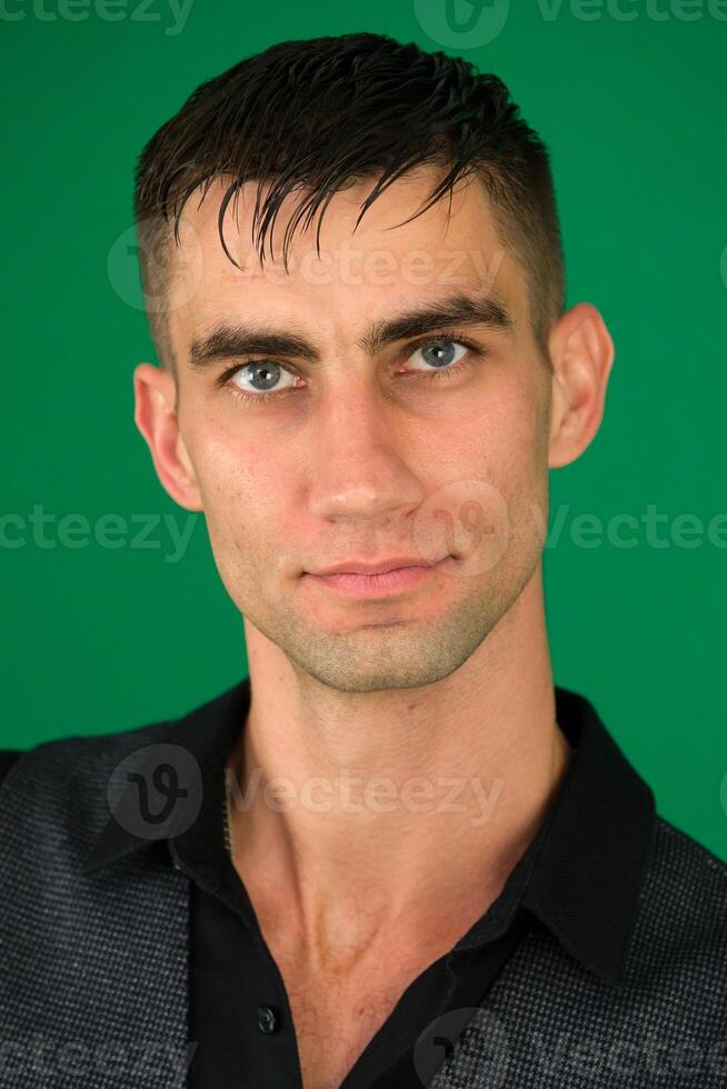 Young businessman isolated against emotions of a handsome man guy on a green background chromakey close-up dark hair young man photo