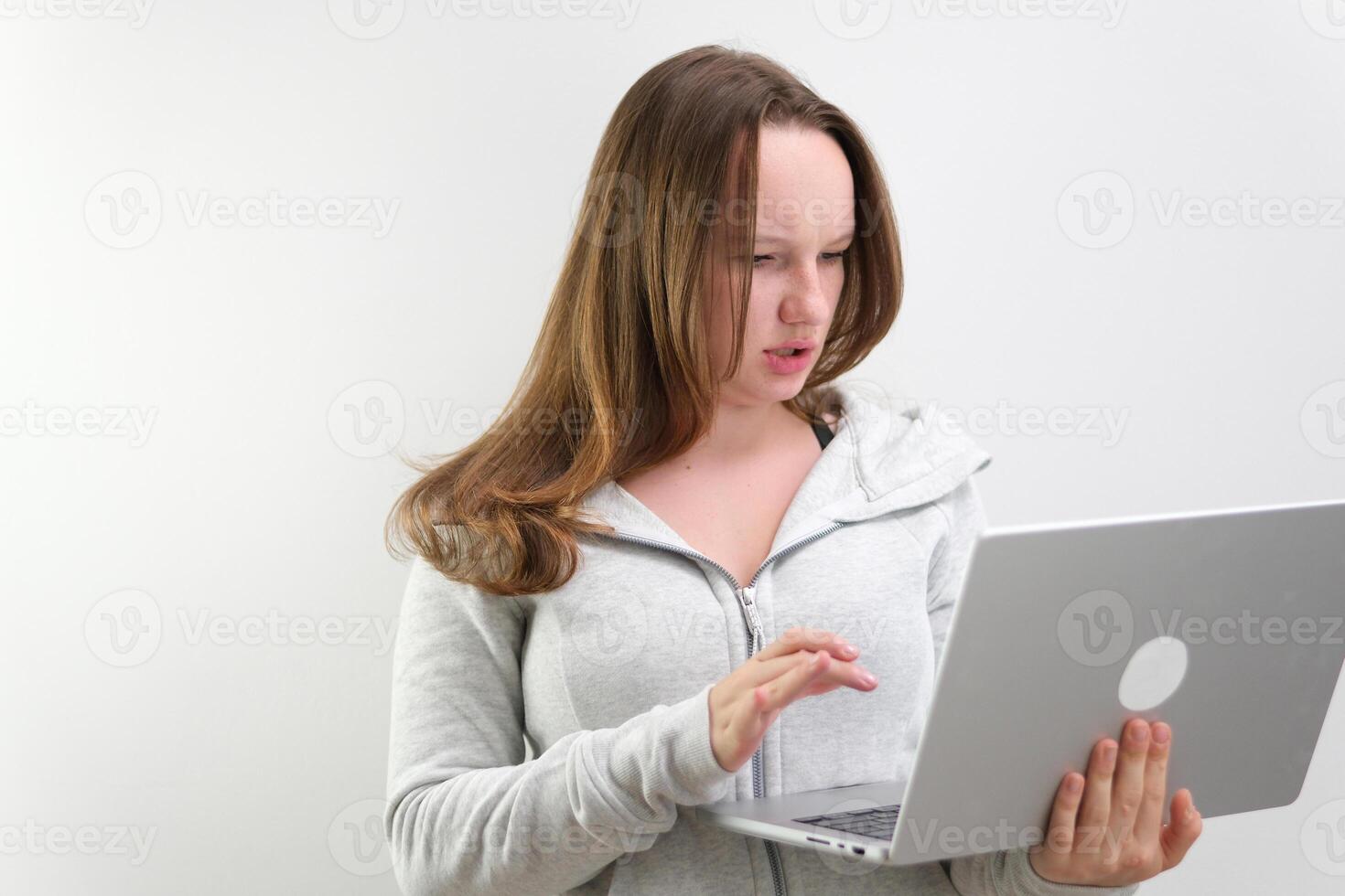 A young female student sitting at the table, using headphones when studying. photo