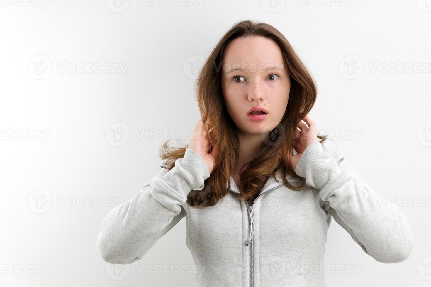 surprise young teen girl looks to side mouth open turns eyes to camera What happened what is this interesting facial expression emotions in studio on white background advertising space for text beauty photo