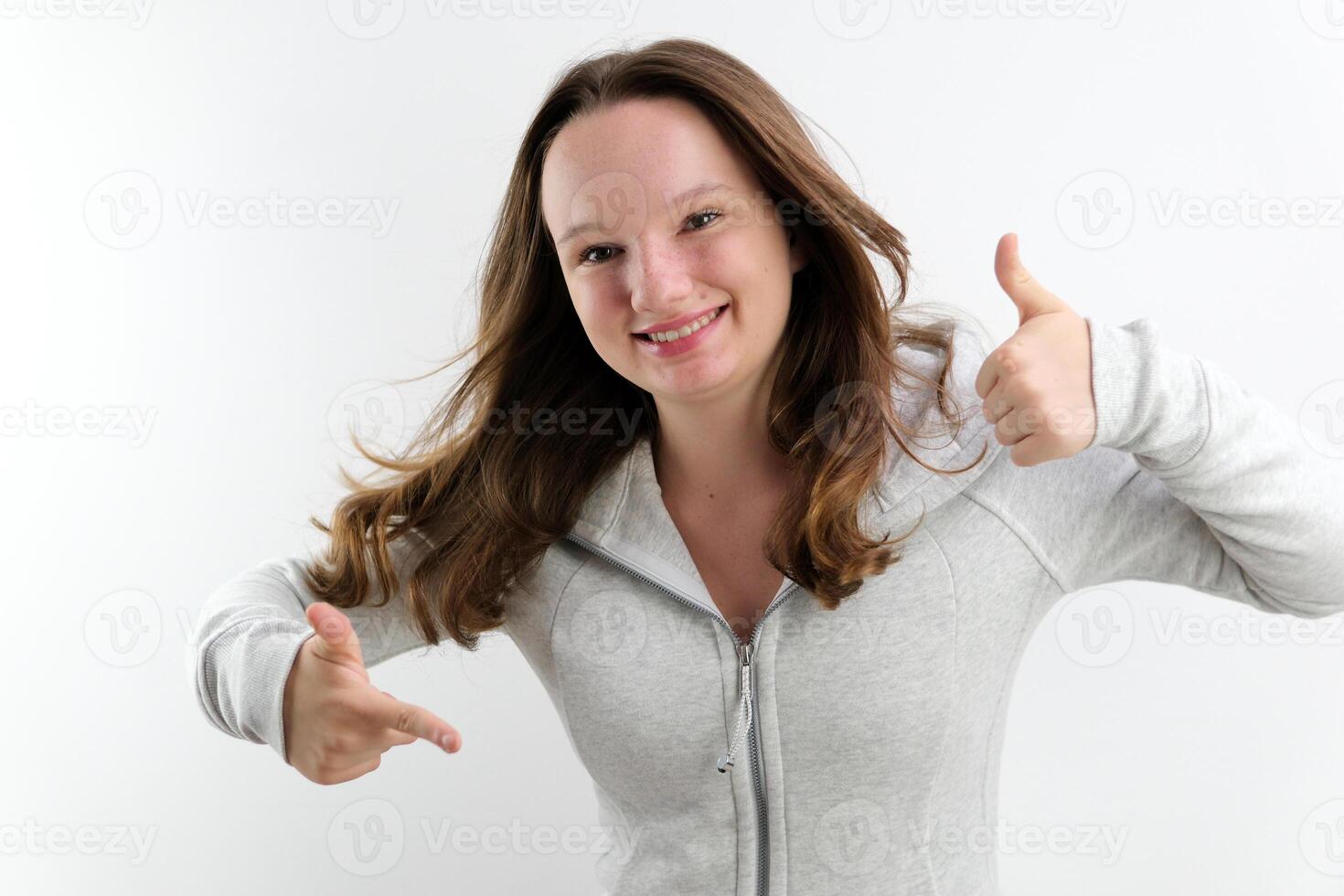 teenage girl cheerfully jumps and shows Finger to the side and the other hand thumbs up approval offer take buy it Good advertising space for text cheerful teenager adolescence wonderful product photo