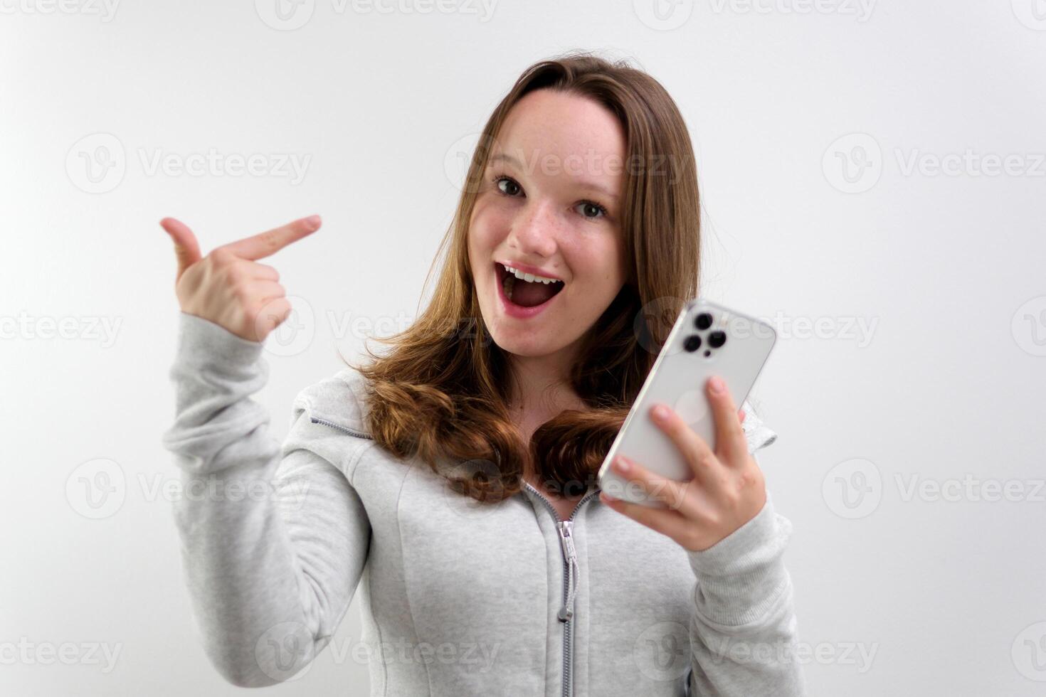 Look Here. Happy Woman Showing Blank Smartphone Screen and Pointing On It, white Background photo