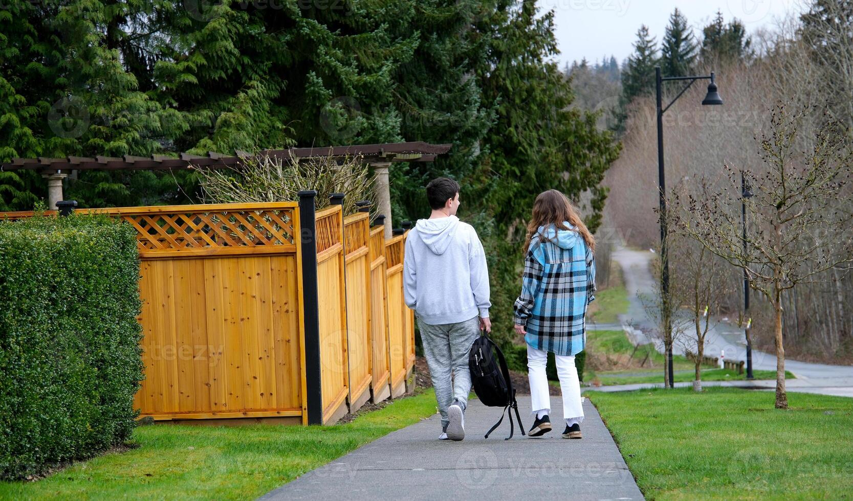 Young man and woman walking together on street in nature on sunny day photo