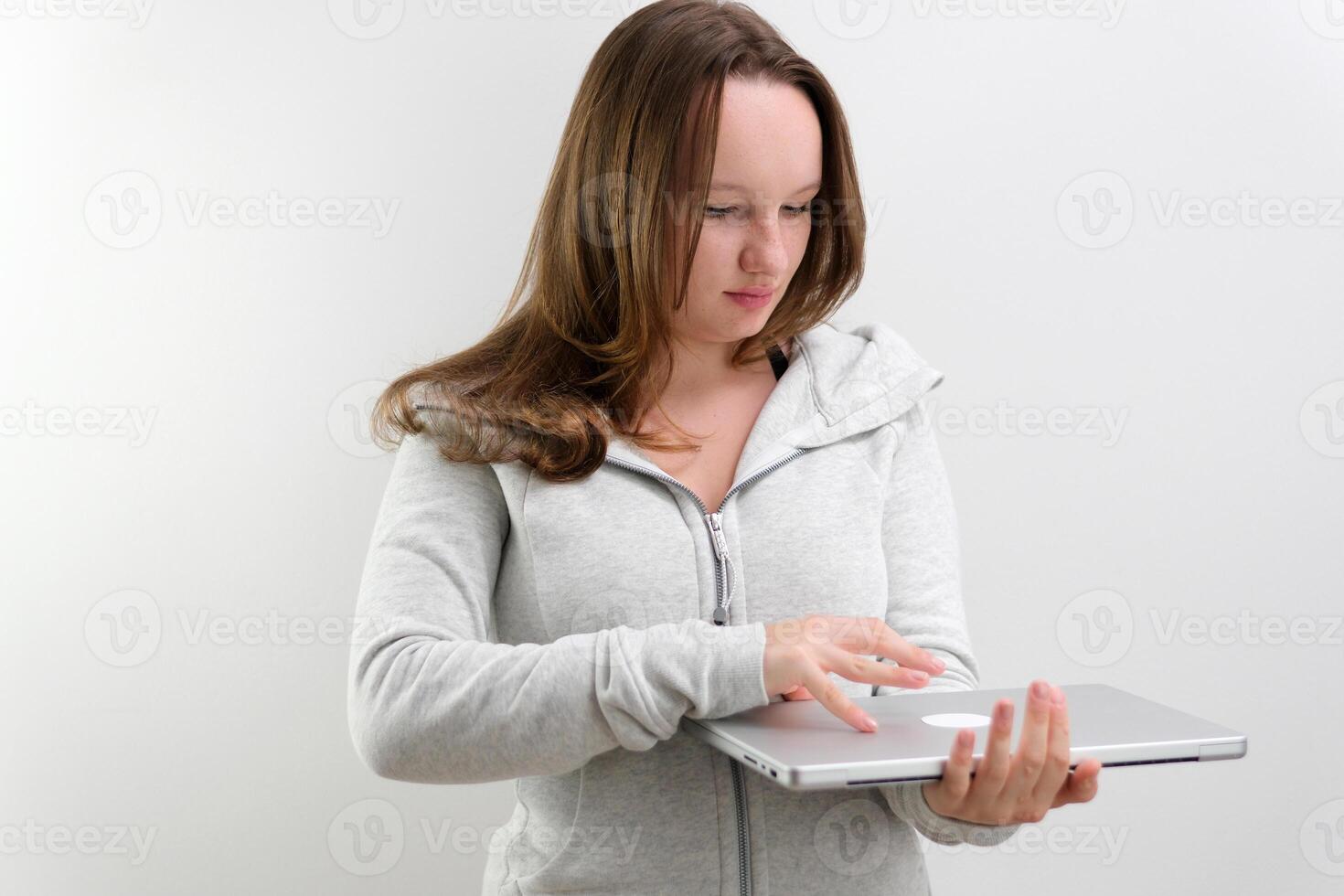 young teenage girl rejoices at the new laptop hugs smiling gray gadget closes looking at it tenderness joy gift winning on a white background young woman studio photo