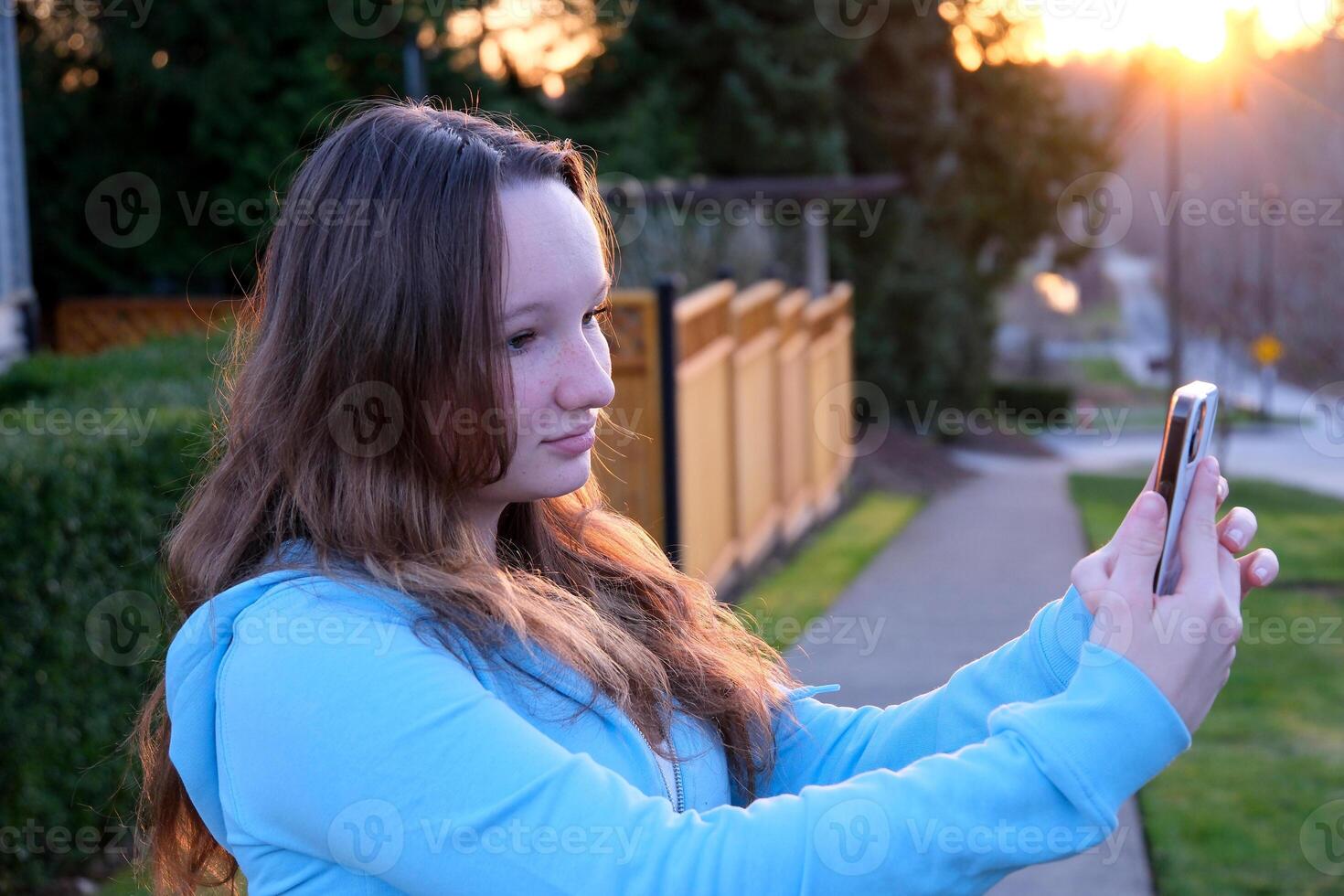 face of beautiful young girl looking at phone turn head look into camera close-up tenderness modesty purity beauty virginity straighten hair embarrassment sincerity in the eyes of adolescence teenager photo