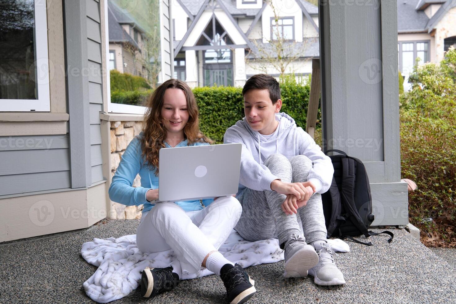 education, technology, school and internet concept - three smiling students with laptop, tablet pc and notebooks at school photo