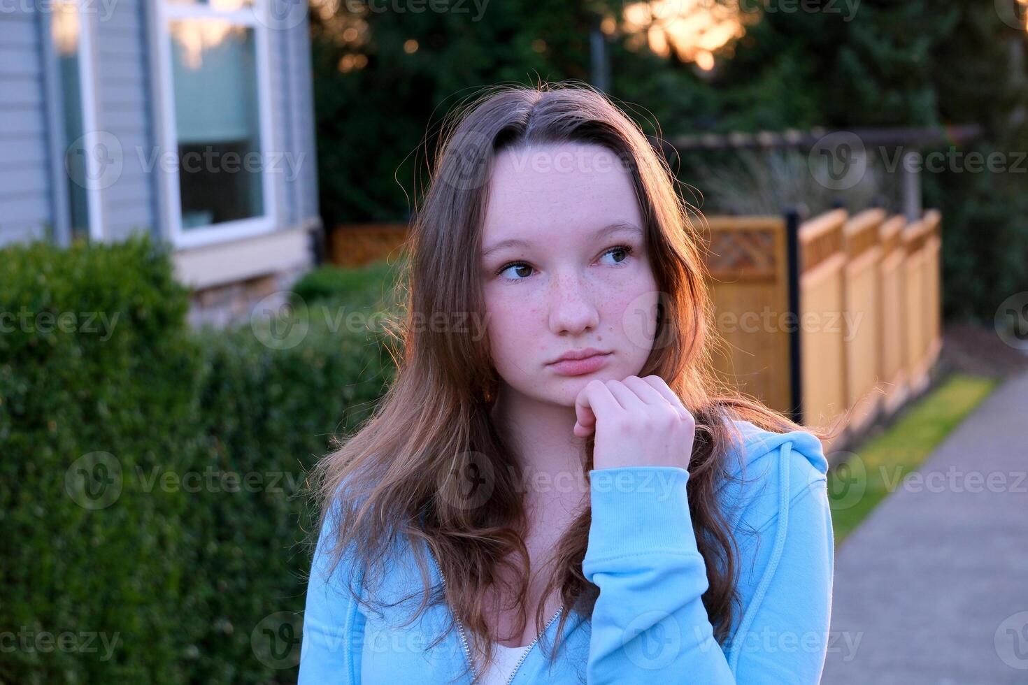 Portrait of a beautiful young girl looking into the camera and smiling. A charming woman dressed in a luxurious is standing on the street. photo