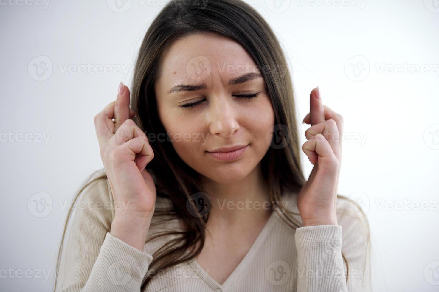 the girl crosses her fingers in front of her face makes a wish worries thinks hopes and waits Pleased attractive European woman makes wish to win, raises hands with crossed fingers, waits photo