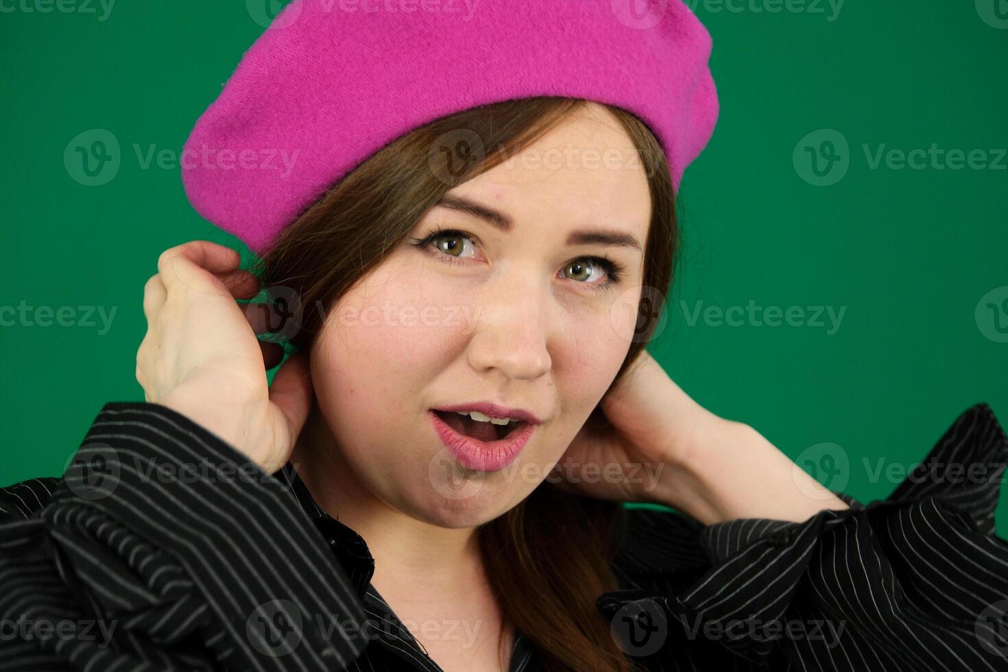 Portrait of young french style woman woman on a green background chromakey in a black striped mens shirt different emotions facial expression close-up advertising space for text clean. kind eyes photo