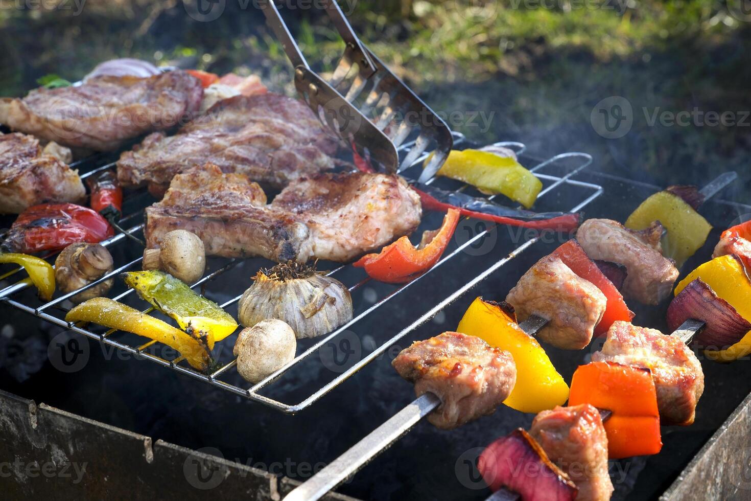 Barbecue or kebab cooked on the grill on hot coals with grilled vegetables. Slices of grilled pork on metal skewers. photo