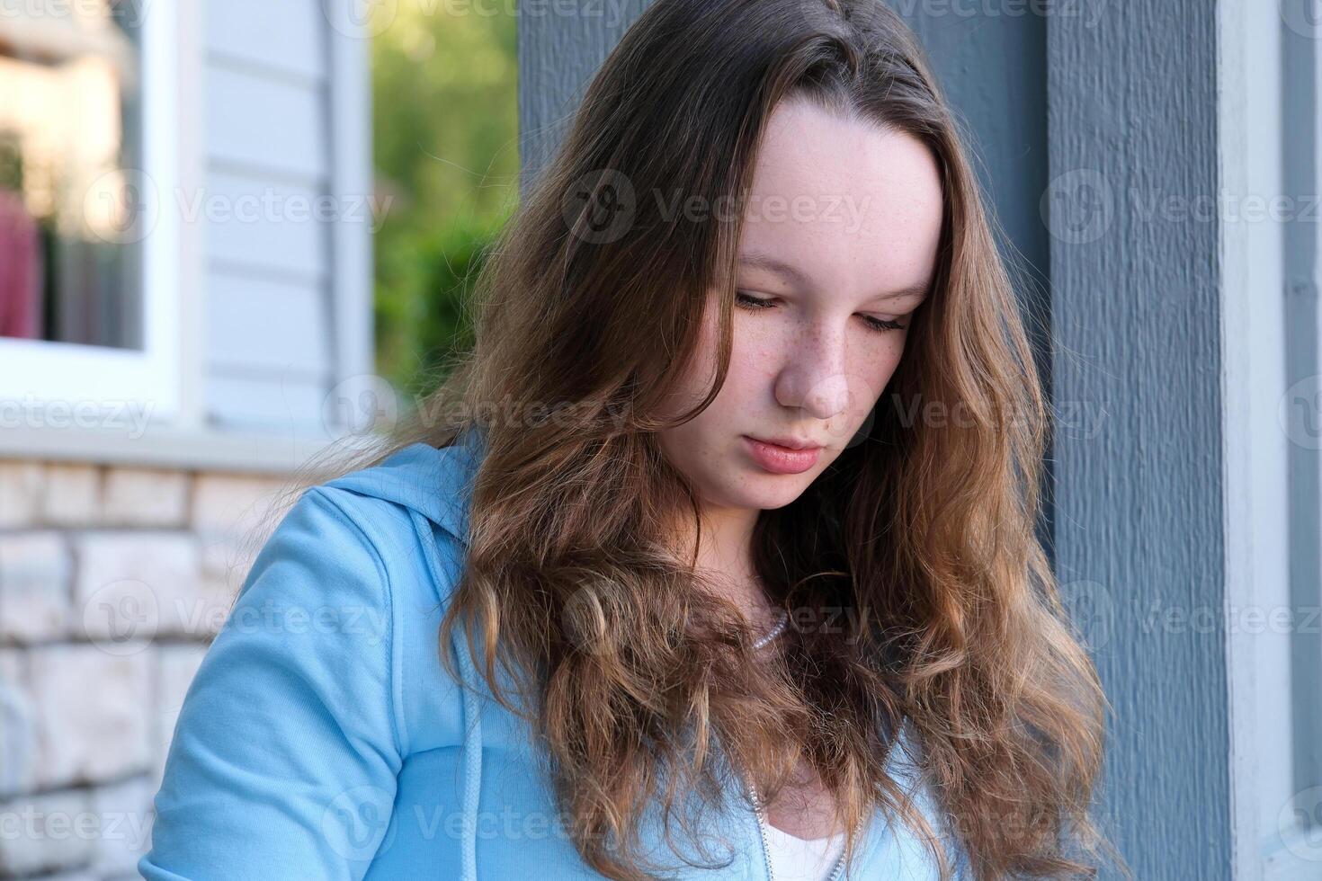 beautiful face of a young teenager girl close-up girl leaned over draws or writes looks down against very beautiful reflections work training lessons thinking dreaming expectation sadness photo