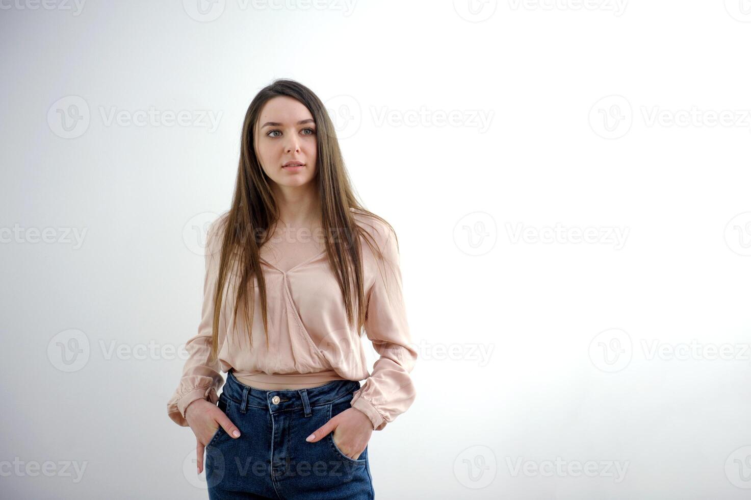 Close-up young slender woman holding her hands at waist of her jeans on white studio background. photo